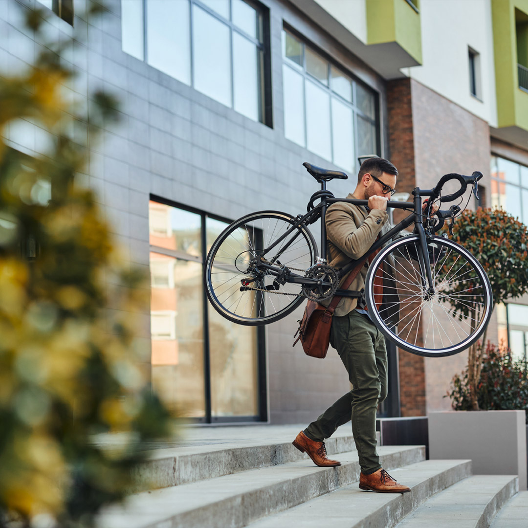 freetime_san_lazzaro_city_green Man in the casual business wear carrying his bike on the shoulder down the stairs. He sustainably commutes